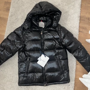 Svart Moncler Maya - Intressekoll på min svarta jacka från Moncler i bra skick, modellen Maya. Jackan är perfekt för vintern med sin varma och vadderade design. Den har en dragkedja framtill och två praktiska fickor med dragkedjor. Passformen är normal och den är även unisex. Jackan är i storlek 1. Scan finns och dustbag medföljer. Små defekter finns då jackan använts. Jackan är tidigare köpt här på Plick! Säljer möjligen för att jag är sugen på en ny vinterjacka. Hör av dig vid funderingar!