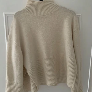 Beige stickad polotröja - Mysig beige stickad polotröja i oversized stil. Perfekt för kalla höst- och vinterdagar, men också till jul eller nyår!  Den har långa ärmar och en ribbad kant nedtill som ger en snygg detalj. Tröjan är superbekväm, jag skulle styla med en svart min kjol eller jeans.  Färgen är Creme vit! 