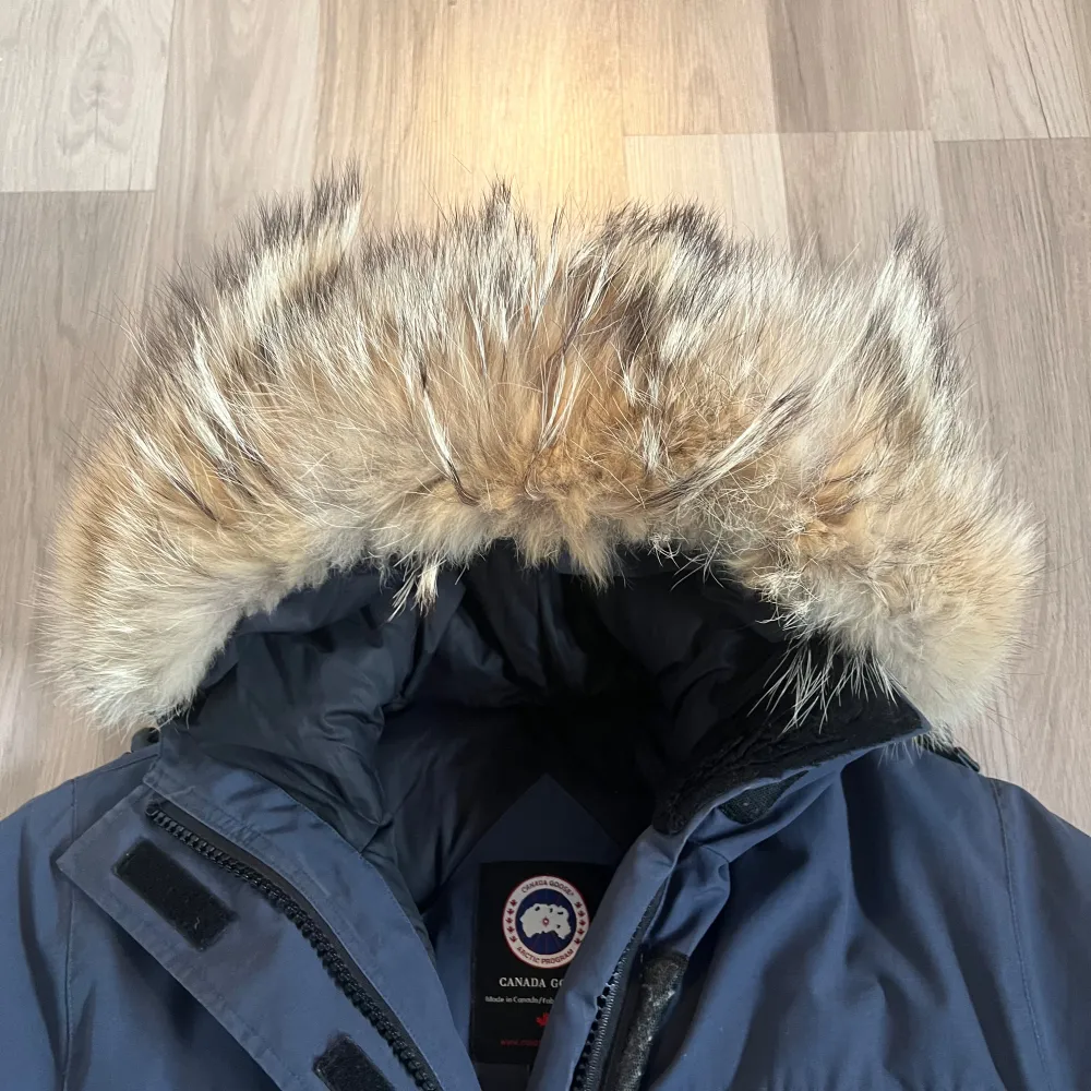 Säljer en snygg blå parkajacka från Canada Goose i mycket bra skick. Jackan har en stor huva med pälsdetalj och flera praktiska fickor. Perfekt för kalla vinterdagar! 🧥❄️. Självklart äkta. Köpt på NK Stockholm. Toppenskick. Inte hål, revor. Muddar hela o fina. . Jackor.