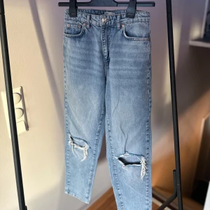 Blå jeans med slitningar - Super snygga blåa jeans från Gina Tricot  i storlek 36. Slitningar på knäna och en klassisk femficksdesign. Högmidjade och i bra skick!