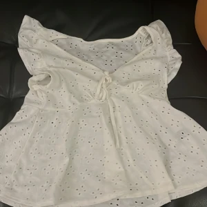 Vit blus med knytning - Säljer en söt vit blus med knytning framtill. Den har ett broderat mönster och korta ärmar. Perfekt för sommardagar eller en avslappnad vårlook. Blusen har en v-ringad design och är i mycket bra skick. Har fått jätte många komplimanger med denna. Köpte för 250. Den e storlek S men är väldigt elastisk så passar M också. Använt en gång innan