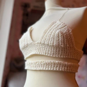 Beige virkad linnetopp - Säljer en superfin beige virkad linnetopp som är perfekt för sommaren. Den är ärmlös och har en croppad design med en ribbad struktur. Toppen är både bekväm och stilren, perfekt för varma dagar eller som ett lager under en kofta.