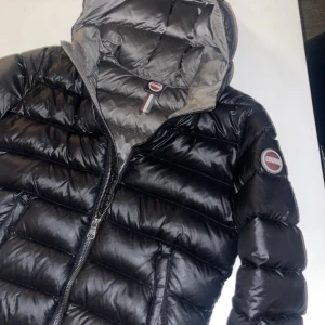 Svart dunjacka från Colmar - Säljer en snygg och varm svart dunjacka från Colmar. Jackan har en praktisk huva och dragkedja framtill. Perfekt för kalla vinterdagar och håller dig varm och stilren. Den är i mycket bra skick! Storlek L/154 i barn men är samma storlek som en xs i dam, köpt för 4500 och knappt använd (pris kan diskuteras), säljer pga at den inte kommer till tillräckligt mycket användning då jag har en annan liknade jacka!