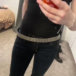 Svart nitat bälte - Säljer ett coolt svart bälte med silverfärgade nitar. Perfekt för att ge din outfit en edgy touch. Bältet har en klassisk stil med en rad av fyrkantiga nitar och en robust spänne. Passar både till vardags och fest. 🖤