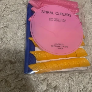 Spiral Curlers - Säljer ett set med Spiral Curlers för att skapa perfekta lockar utan värme. Paketet innehåller 8 hårspolar i olika färger och en krok för enkel applicering. Perfekt för att få snygga lockar på ett skonsamt sätt!