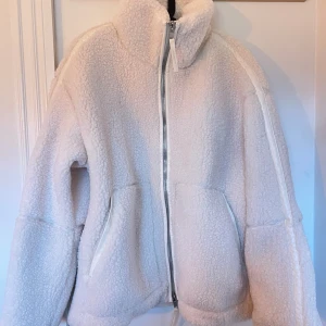 Vit teddyjacka från H&M - Säljer en supermysig vit/beige populär och slutsåld teddyjacka från H&M i storlek M. Jackan är helt oanvänd i nytt skick och kommer i originalförpackning.