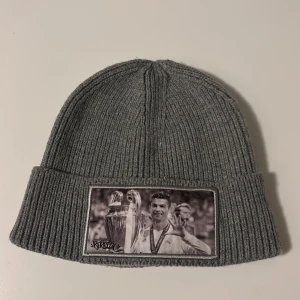 En produkt 100kr Grå och svart ribbade mössor samt kepsar med fototryck - Säljer två ribbade mössor i grått och svart med coolt fototryck på framsidan. Dessutom finns två kepsar, en i beige och en i ljusblått, båda med fototryck. Perfekta för att ge din outfit en unik touch!