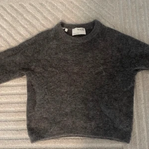 Grå stickad tröja från Selected Femme - Mysig grå stickad tröja från Selected Femme i storlek S. Perfekt för kyliga dagar med sin mjuka och varma känsla. Tröjan har en klassisk design med långa ärmar och rund hals. Passar både till vardags och lite finare tillfällen. 