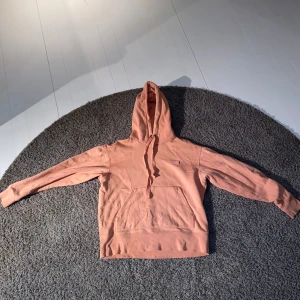 Rosa hoodie från Acne Studios - Säljer en superfin rosa hoodie från Acne Studios i storlek S. Den är gjord av mjuk bomull och har en klassisk känguruficka framtill. Perfekt för både mysiga hemmakvällar och vardagsäventyr. Den har en liten broderad logga på bröstet som ger en stilren touch. Passa på att fynda denna snygga tröja!
