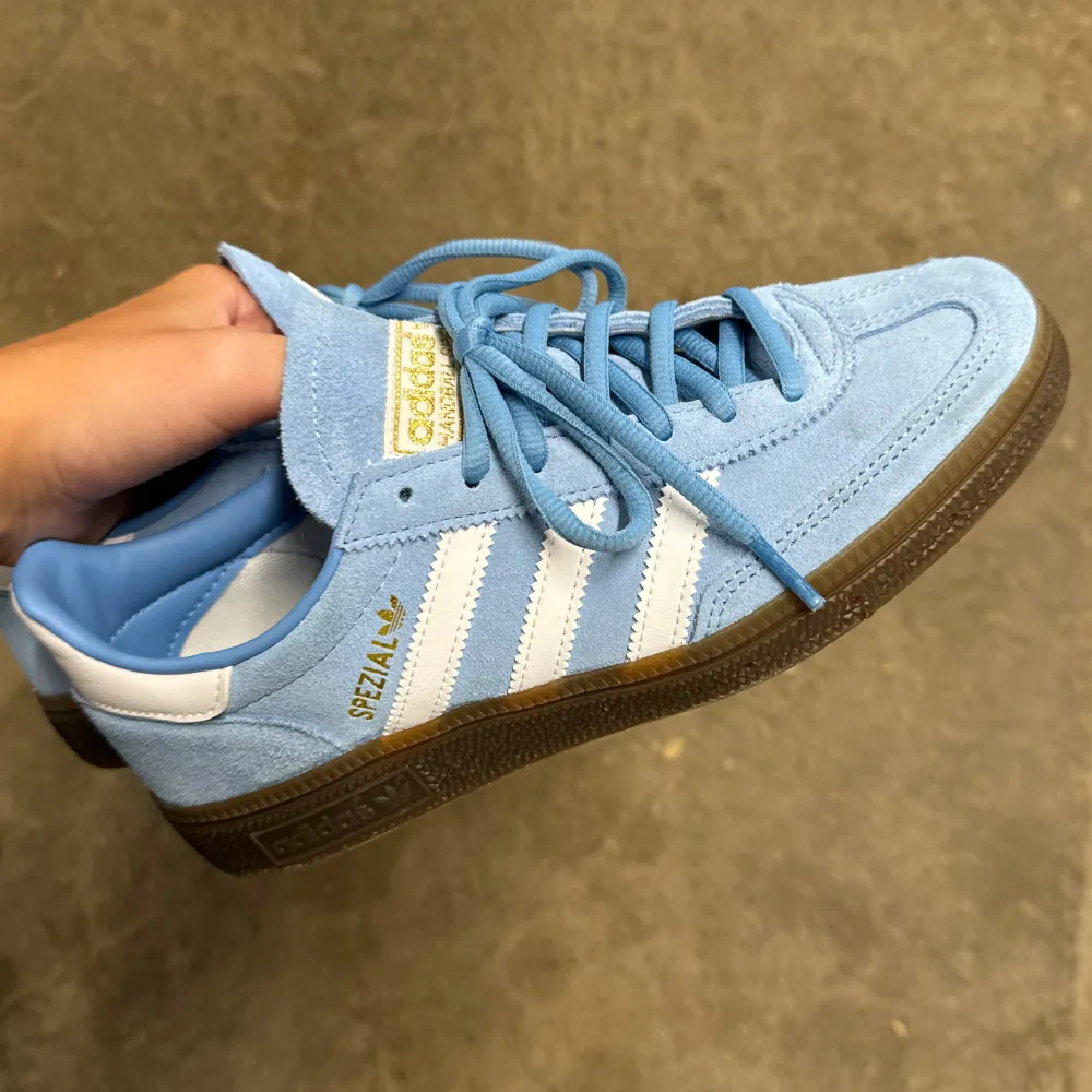 Snygga Adidas Spezial sneakers i ljusblå mocka med vita detaljer och bruna sulor. Använda väldigt få gånger!!!! Som nya ! Storlek 38 . Skor.