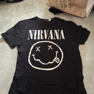 Svart Nirvana t-shirt från H&M Divided - Säljer en svart t-shirt från H&M Divided. Trycket är intakt och inte sprucket 