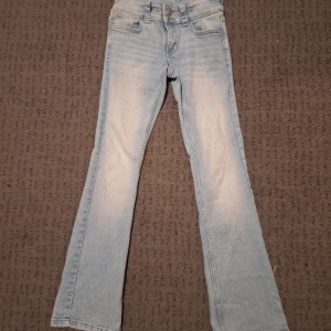 Ljusblå bootcut jeans från H&M - Säljer ett par ljusblå bootcut jeans från H&M i storlek 158. De har en låg midja och klassisk femficksdesign med detaljer på bakfickorna. Aldrig använda! 💞