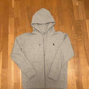 Grå hoodie från Polo Ralph Lauren - Säljer helt ny Polo Ralph Lauren Zip Hoodie! Storlek M. Hör av er vid funderingar🤗