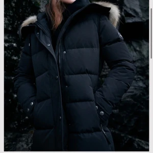 Svart dunjacka med pälskrage - Riktigt varm och i utmärkt skick. Jackan är av hög kvalitet och har ett originalpris på 6000kr. Lite större i storlek och har använts sällan.