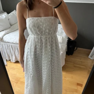 Vit klänning med snörning i ryggen - Superfin vit långklänning med blommdetaljer och smala axelband. Ryggen har supersnygg snörning som är justerbar. Perfekt för midsommar eller studentmottagning. Säljer då den är för kort på mig som är 172 💫
