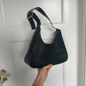 svarr axelväska  - svart axelväska från monki med justerbart spänne på axelremmen!