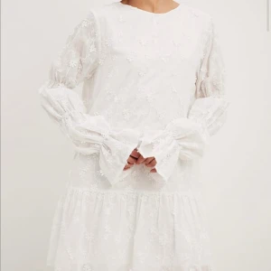 Vit blommig klänning med volangdetaljer - Vit klänning med detaljer från NAKD! Köpt här på Plick men den passade tyvärr inte. Den är helt ny, enbart testad, och med prislappen kvar 🌸storlek S