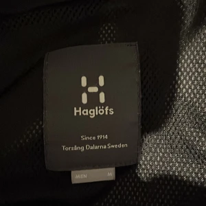 Svart vindjacka från Haglöfs - Säljer en svart vindjacka från Haglöfs i storlek M. Jackan har en praktisk dragkedja och är långärmad med en stilren design. Perfekt för utomhusaktiviteter med sitt lätta och funktionella material.