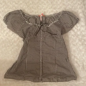 Brun- och vitrutiga blus med spetsdetaljer - Jättesöt brun-och vitrutig blus med knappar och rosett framtill❤️ Den är i storlek medium men passar de flesta eftersom den är stretchig och mjuk. Den är från märket eve of eden❤️Pris går att diskutera❤️