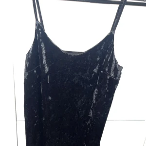 Svart sammet klänning - Snygg svart klänning i mjuk sammet med smala axelband. Perfekt för en elegant look. Klänningen har en enkel och stilren design som passar till många tillfällen.