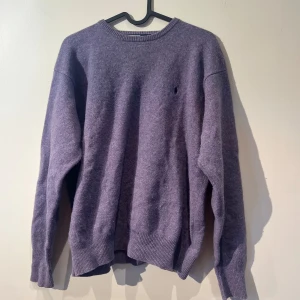 Lila tröja från Ralph Lauren - Säljer en stilren lila tröja från Ralph Lauren. Tröjan har en klassisk design med rund hals och långa ärmar. Den är tillverkad i ett mjukt material som ger en bekväm passform. Perfekt för kyligare dagar. Tröjan är storlek L den har krympt lite i tvätten och sitter nu mer som en M.