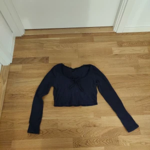Mörkblå croppad topp med knyt - Söt mörkblå croppad topp med långa ärmar och knyt framtill. Storlek M men passformen fungerar för S-M.