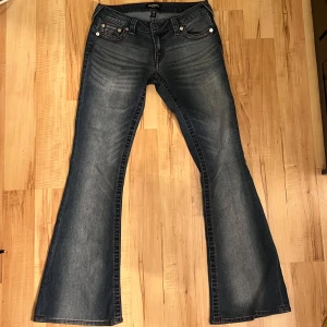 Blåa lågmidjade bootcut jeans från True Religion - Säljer ett par snygga lågmidjade blå bootcut jeans från True Religion. Har aldrig använt dom så de är i nyskick, och köpte dom för 1400kr. Storlek 26. Skriv för mer info 💕
