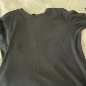 Grå t-shirt från Armani - Säljer en stilren grå t-shirt från Armani med korta ärmar. Den har en diskret logga på bröstet och är tillverkad i mjukt material. Perfekt för en avslappnad look.