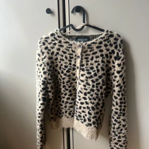 Leopardmönstrad kofta från Stradivarius - Säljer en fluffig leopardmönstrad kofta från Stradivarius i beige och svart. Koftan har långa ärmar och knappar framtill. Köpte i julas, aldrig använd  bara testad 