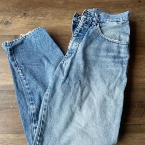 Blåa jeans från Armani Jeans - Säljer ett par snygga blåa jeans från Armani Jeans. De har en klassisk femficksdesign och en dragkedja framtill. Perfekta för en avslappnad stil med en vintage touch. Står ingen storlek men skulle säga dom är som en 36. Fläck på ena byxbenet