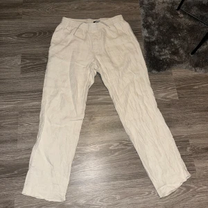 Beige linnebyxor från H&M - Snygga beige linnebyxor från H&M i regular fit. Perfekta för en avslappnad stil med elastisk midja för extra komfort. Passar bra till både vardag och sommarens äventyr.