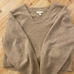 Beige kashmirtröja från H&M - Säljer en mjuk och stilren beige kashmirtröja från H&M. Tröjan har en v-ringad hals och långa ärmar, perfekt för kyligare dagar. Den är i storlek XS och passar utmärkt för en elegant och bekväm look.