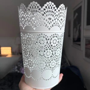 Vit spetsmönstrad kruka - Säljer en elegant vit kruka från IKEA med ett vackert spetsmönster. Perfekt som dekoration eller förvaring. Den har en rund form och är tillverkad i metall. Passar fint i fönstret eller på hyllan för att ge rummet en stilren touch. Säljs pga att den aldrig kommit till användning ☺️