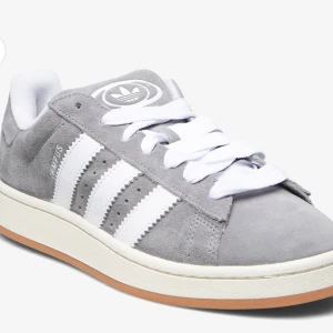 Grå Adidas Campus sneakers - Gråa adidas campus i str 36,5. Har använts 1 gång men säljs för att de är för stora. Gråa skosnören följer med + de vita. Skickas i originalkartong. Skriv privat för bilder på de riktiga skorna! 