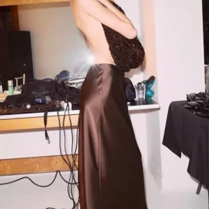 Satin kjol * prislapp kvar ZARA - Elegant brun axelbandslös klänning i ett glansigt material. Perfekt för en stilren och sofistikerad look. Klänningen har en lång och flytande design som ger en vacker siluett.