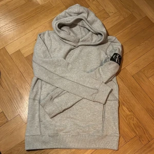 Grå hoodie från Calvin Klein Jeans - Säljer en stilren grå hoodie från Calvin Klein Jeans. Den har en klassisk design med en bekväm huva och ribbade muddar. Perfekt för en avslappnad look. 🩶