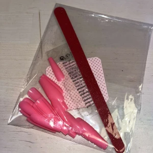 Lösnaglar - Säljer ett set med rosa lösnaglar i olika storlekar tillsammans med en röd nagelfil. Medföljer även lim klister för enkel applicering samf luddfria pads. Perfekt för att fixa snygga naglar snabbt och enkelt hemma. Lösnaglarna har en glansig finish och kommer i en praktisk förpackning.