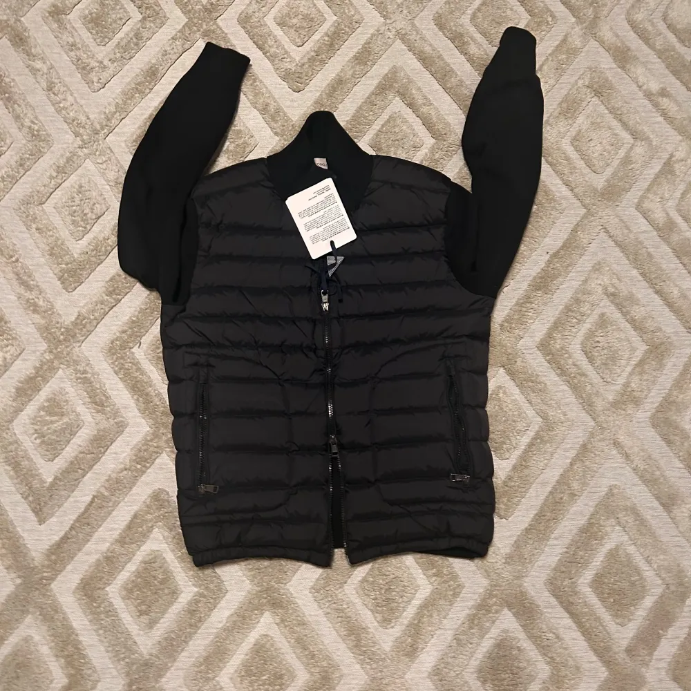 Säljer en snygg svart pufferjacka från Moncler med dragkedja och långärmade ärmar. Jackan har en quiltad design och ett Moncler-märke på ärmen. Perfekt för kyligare dagar.Den är helt ny och aldrig använt.inga skador eller något. Scan funkar.Den är storlek M men passar S också Hör av vid frågor eller Funderingar ⁉️✅ skickas genom 24h✅ kvalité✅. Takit.
