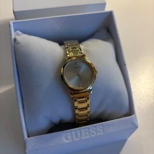 Guldfärgad klocka från Guess! - Guldfärgad klocka från Guess. Det tillkommer extra delar så det går att göra bandet större om det önskas (det går även att göra mindre)!!