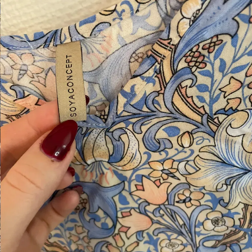 Säljer en söt blommig klänning från Soyaconcept i ljusblått och beige. Klänningen har långa ärmar och ett avslappnat snitt som ger en bekväm passform. Perfekt för en somrig look!. Mekot.