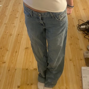 Blå jeansbyxor - Säljer ett par klassiska blå jeansbyxor med en avslappnad passform. Byxorna har en traditionell femficksdesign och är perfekta för en casual look. De är tillverkade i ett slitstarkt denimtyg och har en knapp- och dragkedjestängning.