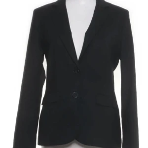 Mörkblå kavaj och kjol från  STOCKH LM - Elegant mörkblå kavaj med två knappar framtill och klassisk krage. Matchande kjol med rak passform. Perfekt för en stilren look.