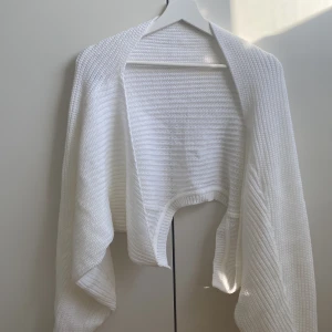 Vit stickad bolerotopp - Säljer en stilren vit stickad bolerotopp. Perfekt för att lägga till en extra touch till din outfit. Den har en öppen design och är gjord i ett mjukt material som ger en skön känsla. Passar bra till både vardag och speciella tillfällen. Den är i storlek L men är lite stor.