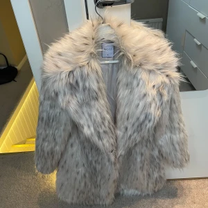 Pälsjacka  - Säljer en lyxig pälsjacka med en fluffig och elegant design. Jackan har långa ärmar och en stor krage. Perfekt för att hålla sig varm och stilren under kyliga dagar. Den är i s men jag skulle verkligen säja att den mer är mot M och siter löst i armarna perfekt storlek.