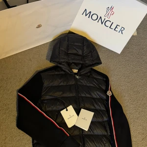 Svart jacka med huva från Moncler - Säljer min Cardigan från Moncler väldigt bra skick inga defekter osv, använd ett fåtal gånger. Köpt i butik i Stockholm (kvitto finns).Allt og finns kvitto box osv. Hör av er vid minsta fråga. Orginal pris 13.