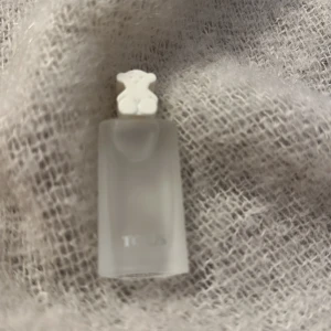 Parfymflaska från Tous - Elegant parfymflaska från Tous med en frostad glasdesign och en söt björnformad kork. Flaskan har en stilren och modern look, perfekt för den som gillar minimalistisk design. Kommer i en matchande vit kartong med Tous-logotypen i silver.