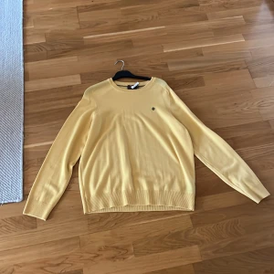 Gul Morris tröja  - Säljer en stilren gul tröja från Morris Tröjan har långa ärmar och ribbade muddar vid ärmslut och nederkant. Perfekt för en avslappnad stil. Finns en liten fläck på bröstet!