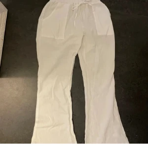Vita linnebyxor med snörning - Snygga vita linnebyxor med avslappnad passform och snörning i midjan. Perfekta för en somrig look. Byxorna har en loose stil och är tillverkade i ett lätt och luftigt material. Säljs då de inte passade, är i fint skick! Pris disskuterbart vid snabb affär!