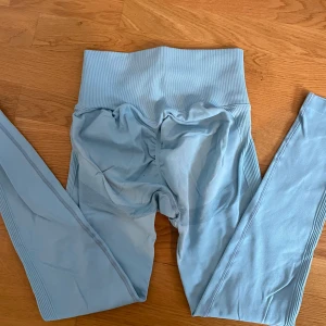 Ljusblå leggings från AW - Snygga ljusblå leggings från AW med hög midja, schrunch baktill och ribbade detaljer längs sidorna. En superfin blå färg som passar bra nu till våren. Det står faktiskt inte vilken storlek de är men skulle säga storlek xs/s. 