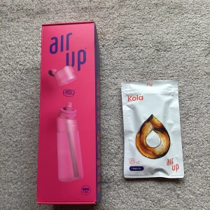 Air Up flaska med kolapods - Jag säljer en oöppnad Air Up flaska i färgen Hot pink med tillhörande kolapods. Flaskan kommer i en snygg rosa och lila förpackning och kolapodsen ger en smak av kola. Perfekt för att smaksätta ditt vatten på ett nytt och innovativt sätt. PS det är den äldre modellen 200 kr för BÅDE flaskan och poddarna. 409 kr kostar det nytt